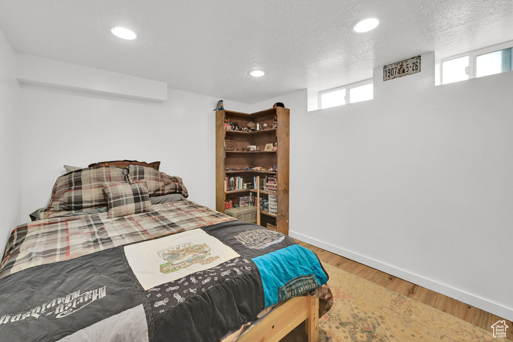 Bedroom with wood finished floors, baseboards, recessed lighting, and a textured ceiling