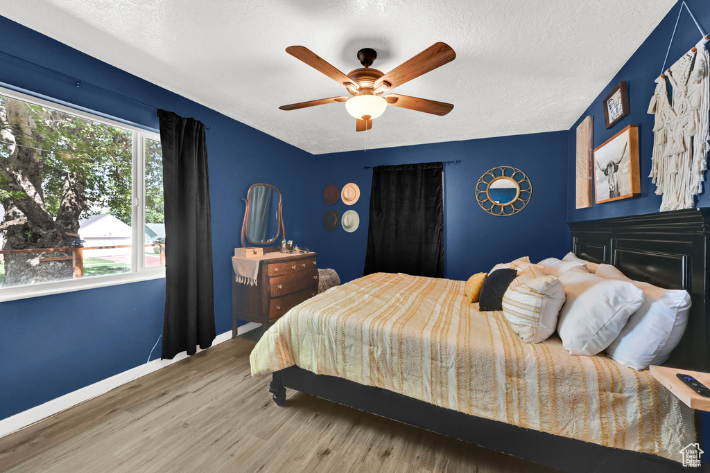 Bedroom featuring a textured ceiling, wood finished floors, baseboards, and a ceiling fan