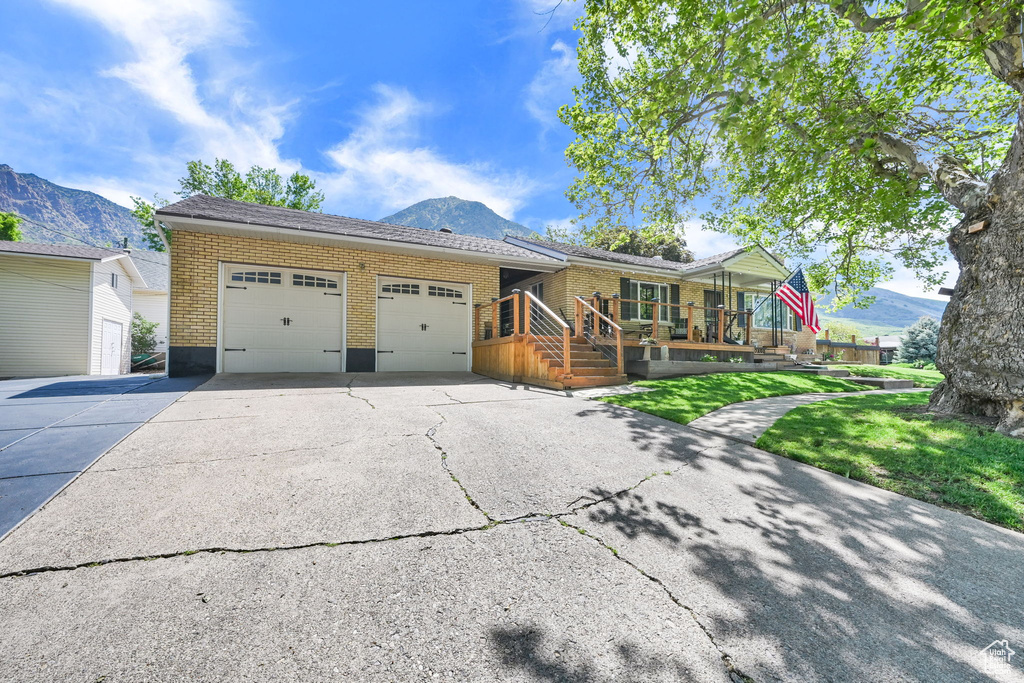 View of front of house featuring an attached garage, a mountain view, brick siding, and concrete driveway