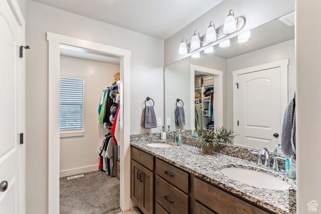 Bathroom featuring baseboards, double vanity, and a spacious closet
