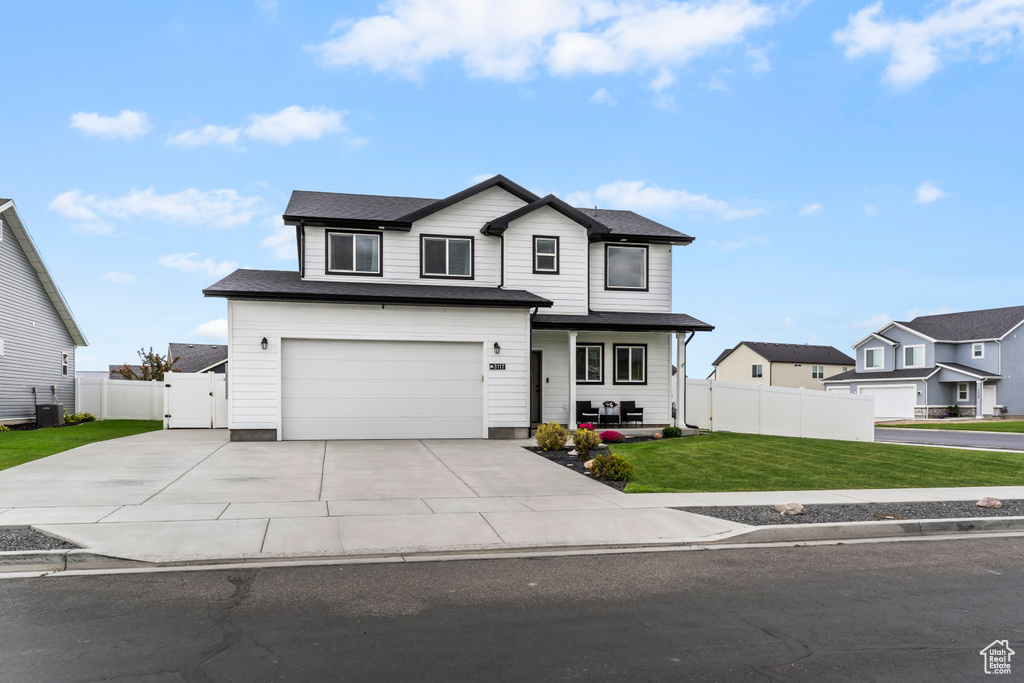 View of front of home featuring an attached garage, a gate, a porch, concrete driveway, and central AC unit