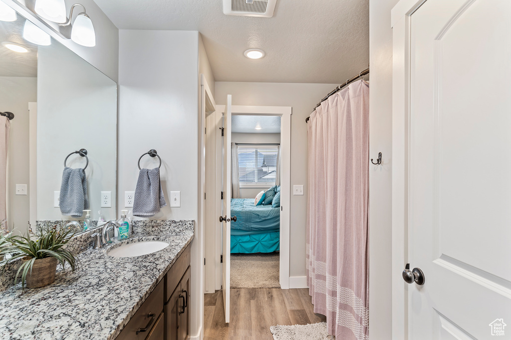 Ensuite bathroom with wood finished floors, vanity, and curtained shower
