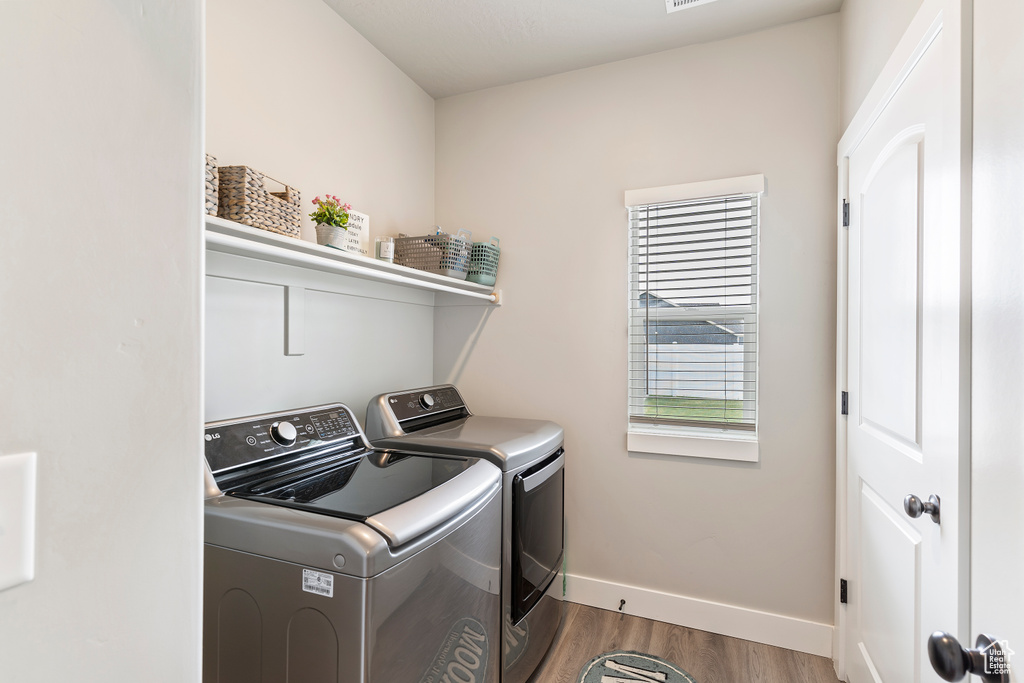 Laundry area featuring washing machine and clothes dryer, wood finished floors, and baseboards