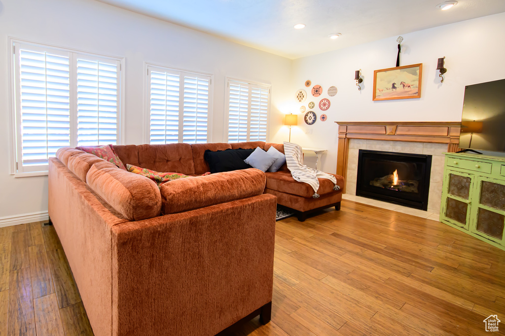 Living room featuring a tiled fireplace, wood finished floors, recessed lighting, and baseboards