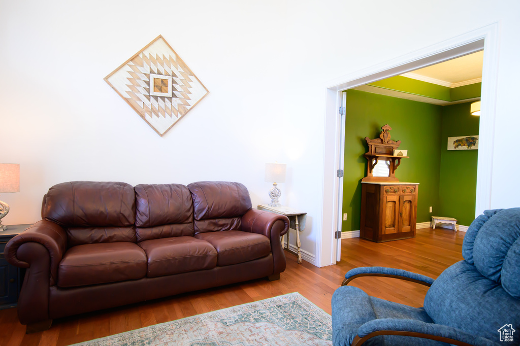 Living area with ornamental molding, wood finished floors, and baseboards
