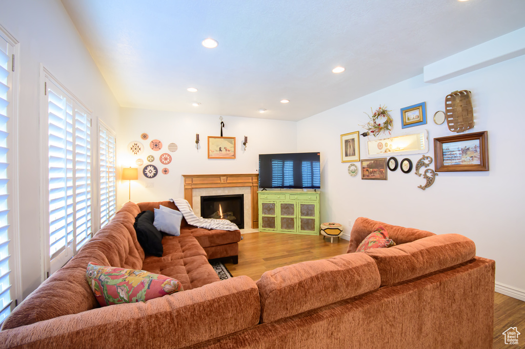 Living area with healthy amount of natural light, wood finished floors, recessed lighting, baseboards, and a lit fireplace