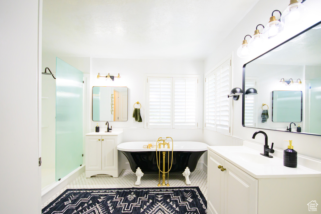 Bathroom featuring a freestanding tub, two vanities, a shower stall, and tile patterned floors
