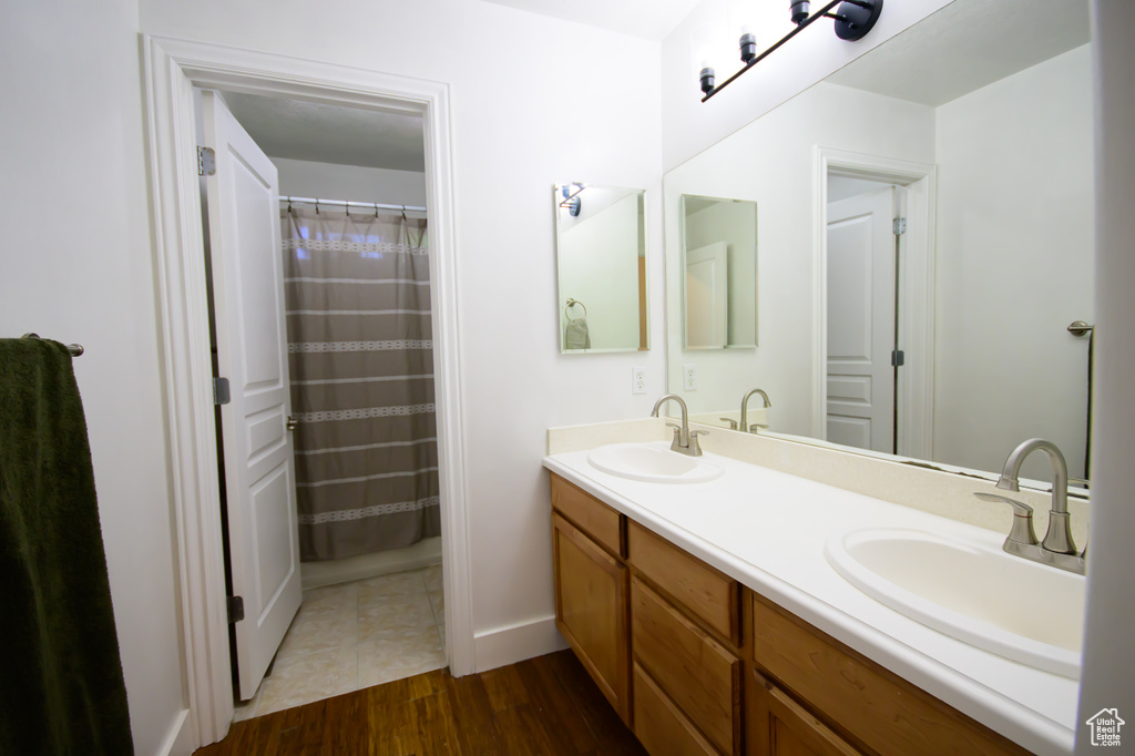 Full bathroom with wood finished floors, double vanity, and baseboards