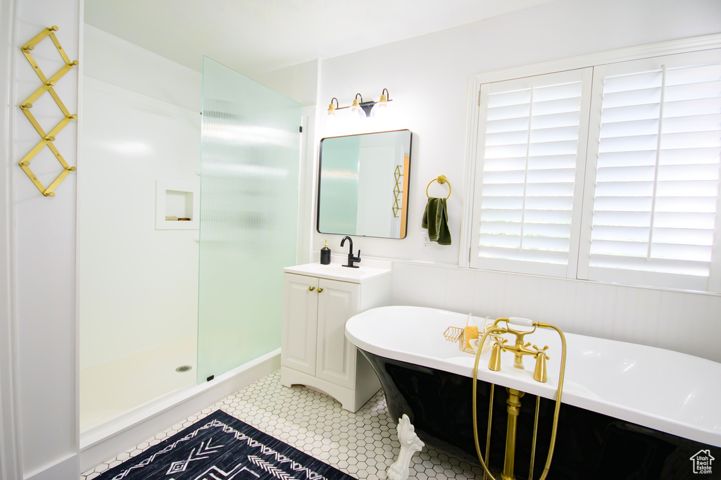 Bathroom featuring a shower stall, tile patterned flooring, a soaking tub, and vanity