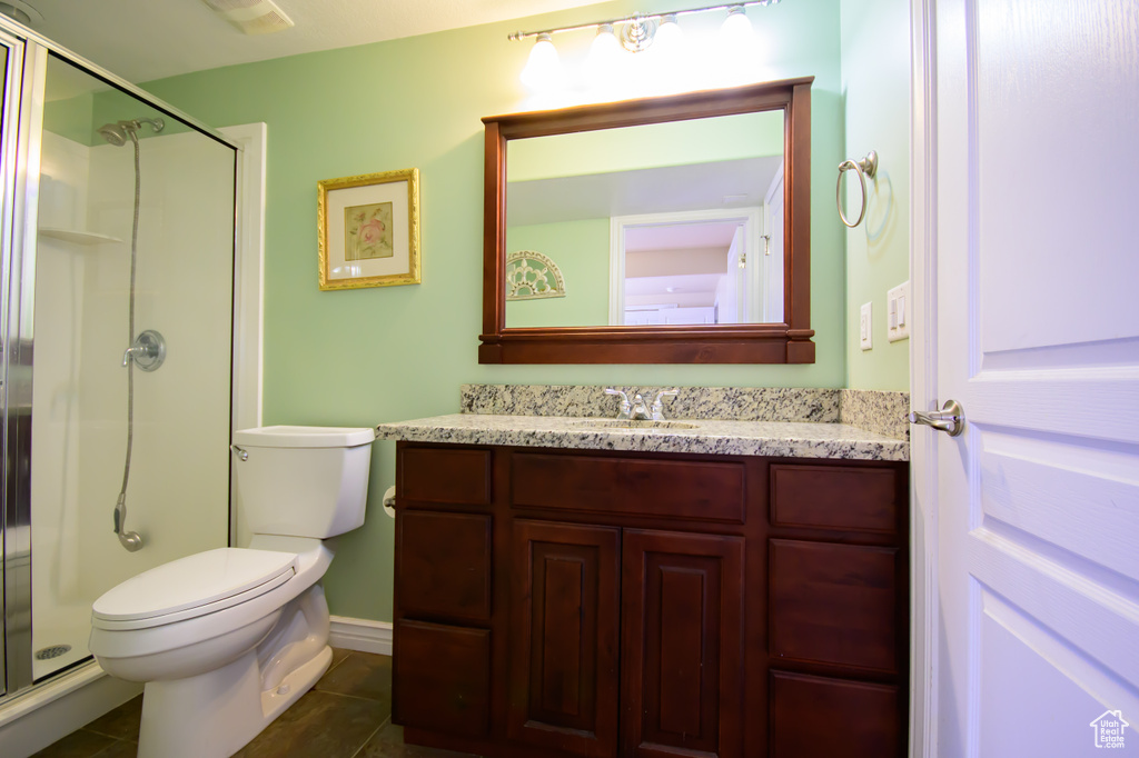 Bathroom with a stall shower, tile patterned floors, vanity, and toilet
