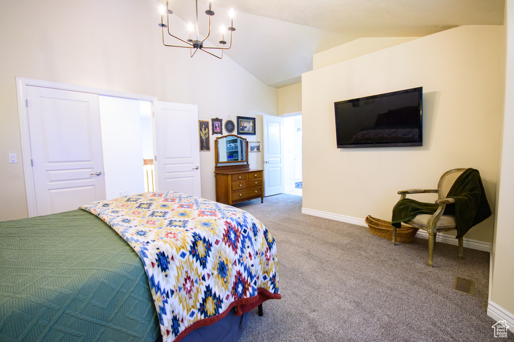 Carpeted bedroom with a chandelier, baseboards, and high vaulted ceiling