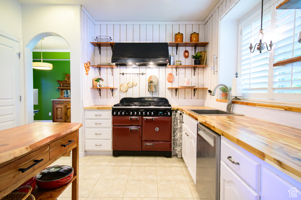 Kitchen with wooden counters, a sink, double oven range, extractor fan, and dishwasher