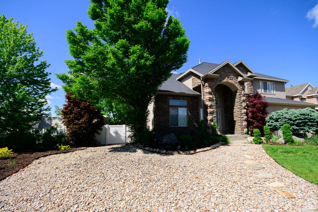 View of front of property featuring stone siding and a gate