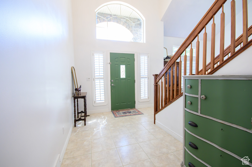 Foyer with baseboards, a towering ceiling, stairway, and tile patterned flooring
