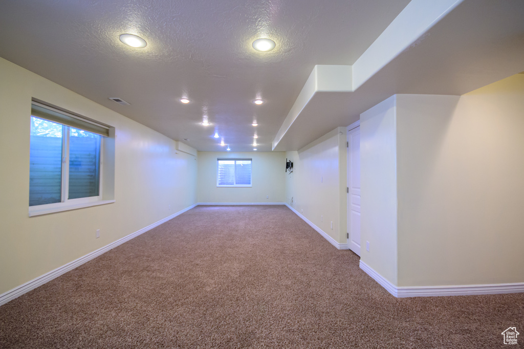 Below grade area with carpet floors, a textured ceiling, baseboards, and recessed lighting
