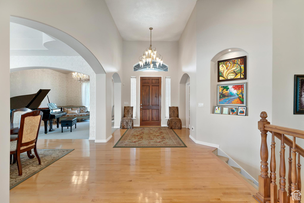 Entryway featuring a chandelier, arched walkways, light wood-style floors, a high ceiling, and baseboards