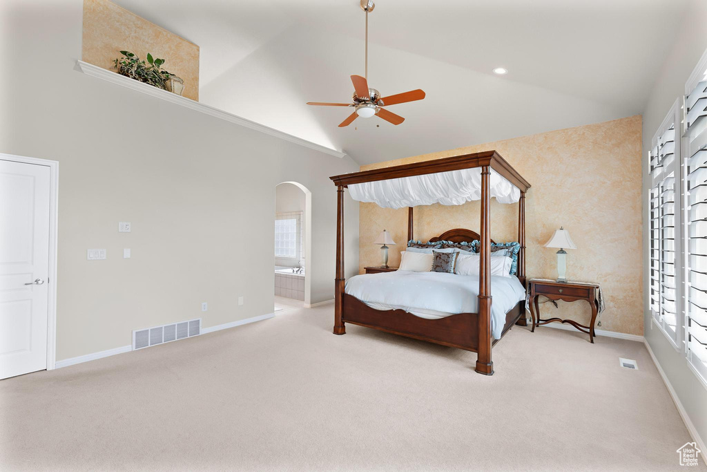 Carpeted bedroom with arched walkways, baseboards, ensuite bath, high vaulted ceiling, and ceiling fan