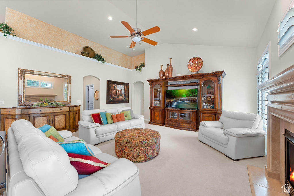Carpeted living area with arched walkways, ceiling fan, a premium fireplace, high vaulted ceiling, and recessed lighting