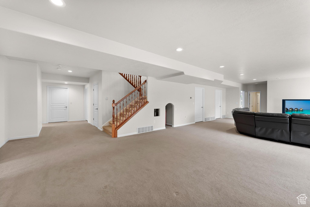 Unfurnished living room with carpet floors, stairs, baseboards, recessed lighting, and arched walkways