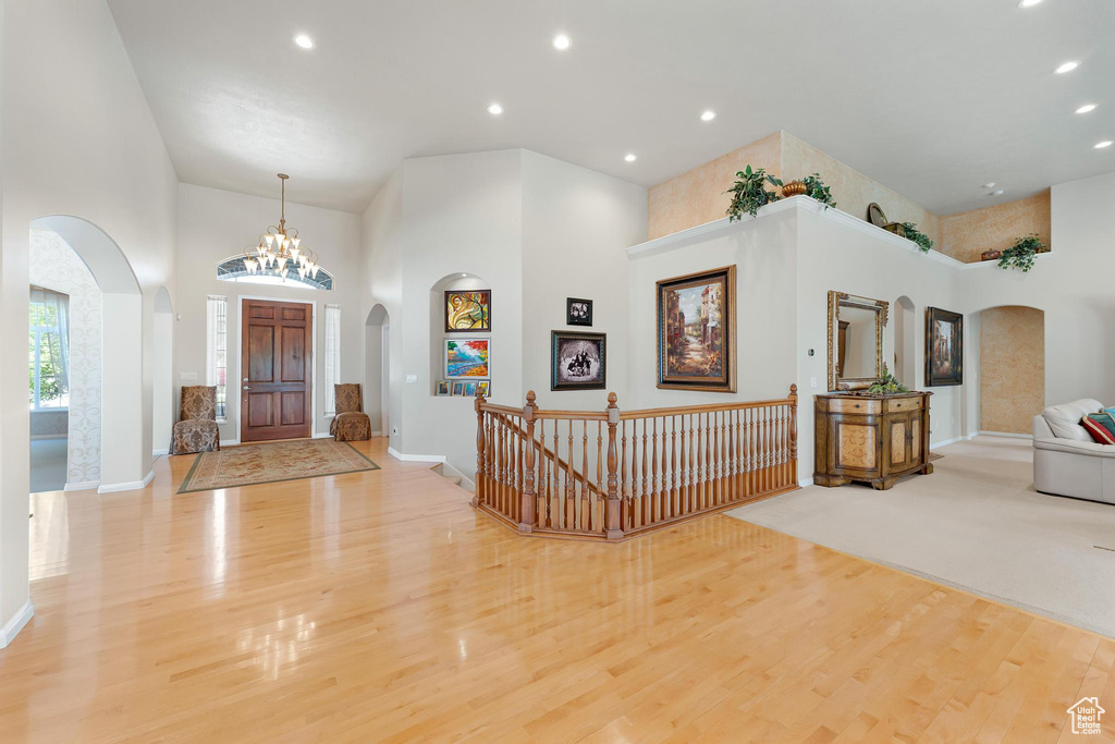 Foyer featuring a high ceiling, arched walkways, wood finished floors, baseboards, and recessed lighting