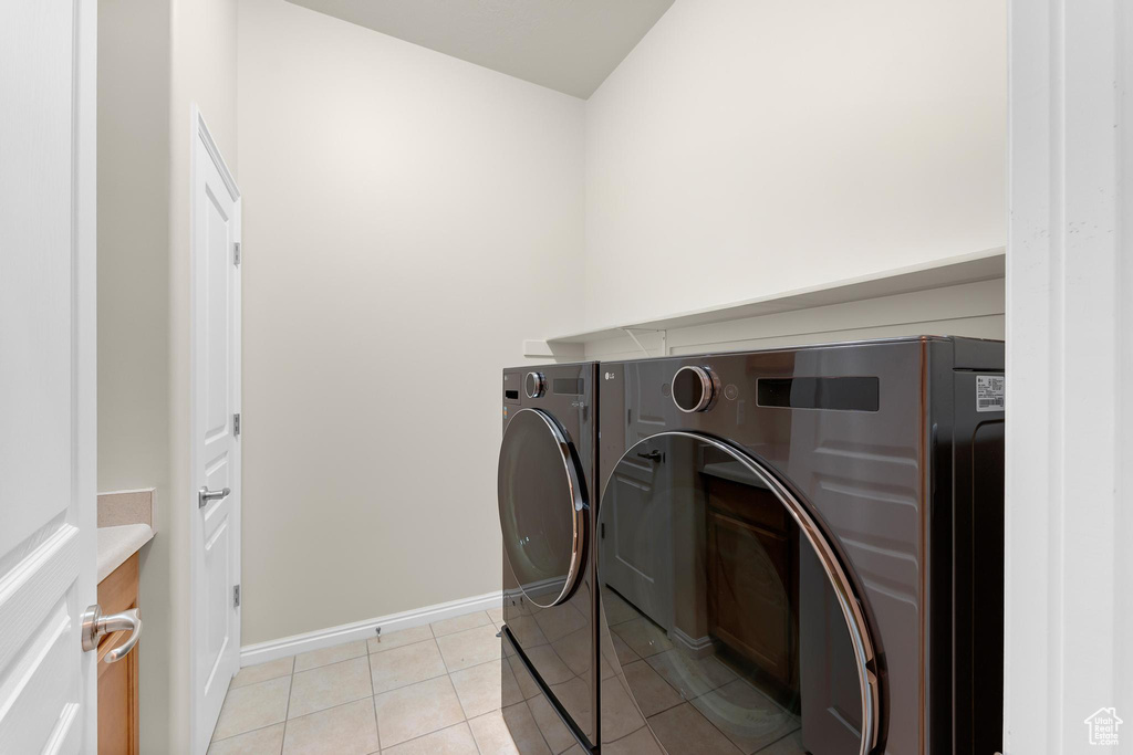 Laundry area with independent washer and dryer, baseboards, and light tile patterned floors