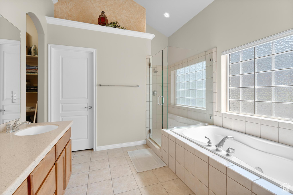Full bath with a shower stall, a garden tub, lofted ceiling, tile patterned flooring, and vanity