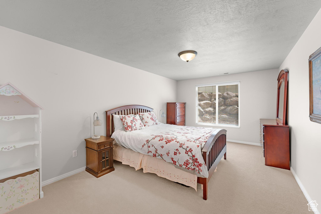 Carpeted bedroom with baseboards and a textured ceiling
