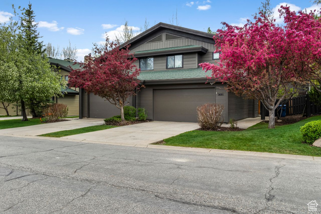 View of front facade with concrete driveway, a garage, and a front yard