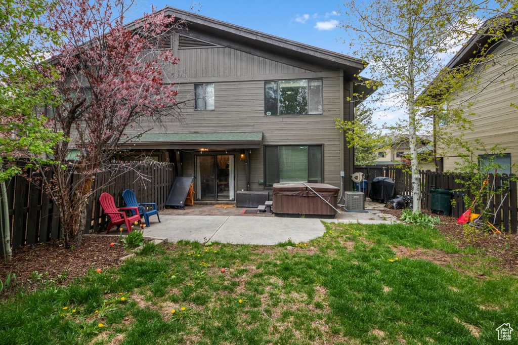 Rear view of property featuring a hot tub and a patio