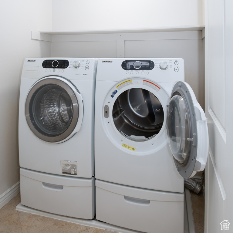 Clothes washing area featuring washer and dryer and light tile patterned floors