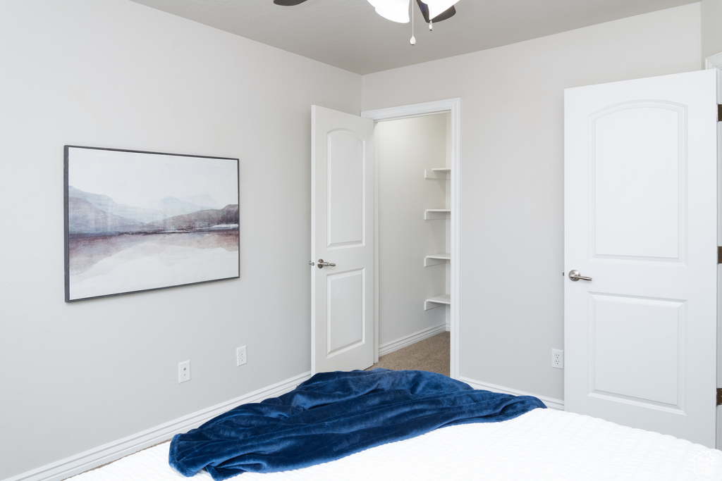 Bedroom featuring a spacious closet, carpet, a ceiling fan, and baseboards