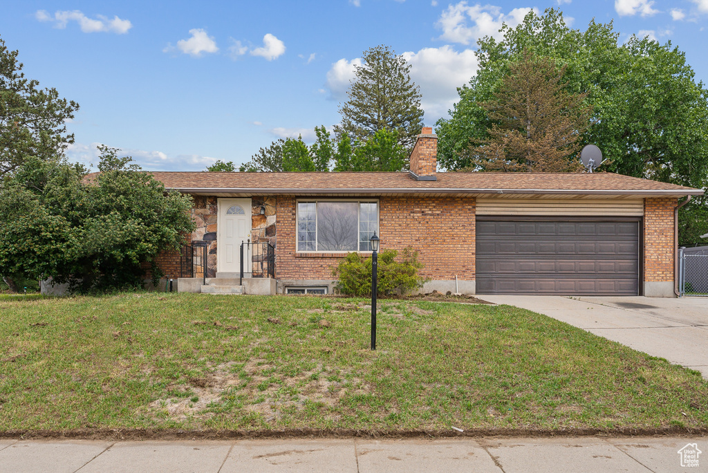 Ranch-style home with a garage, driveway, a front lawn, and a chimney