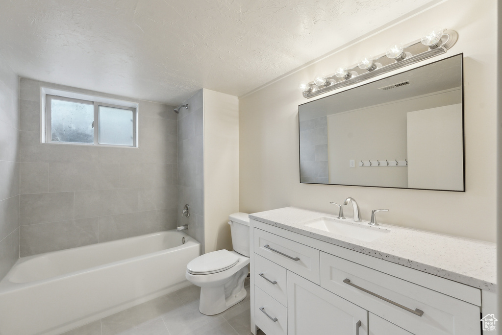 Bathroom with tile patterned flooring, toilet, washtub / shower combination, vanity, and a textured ceiling