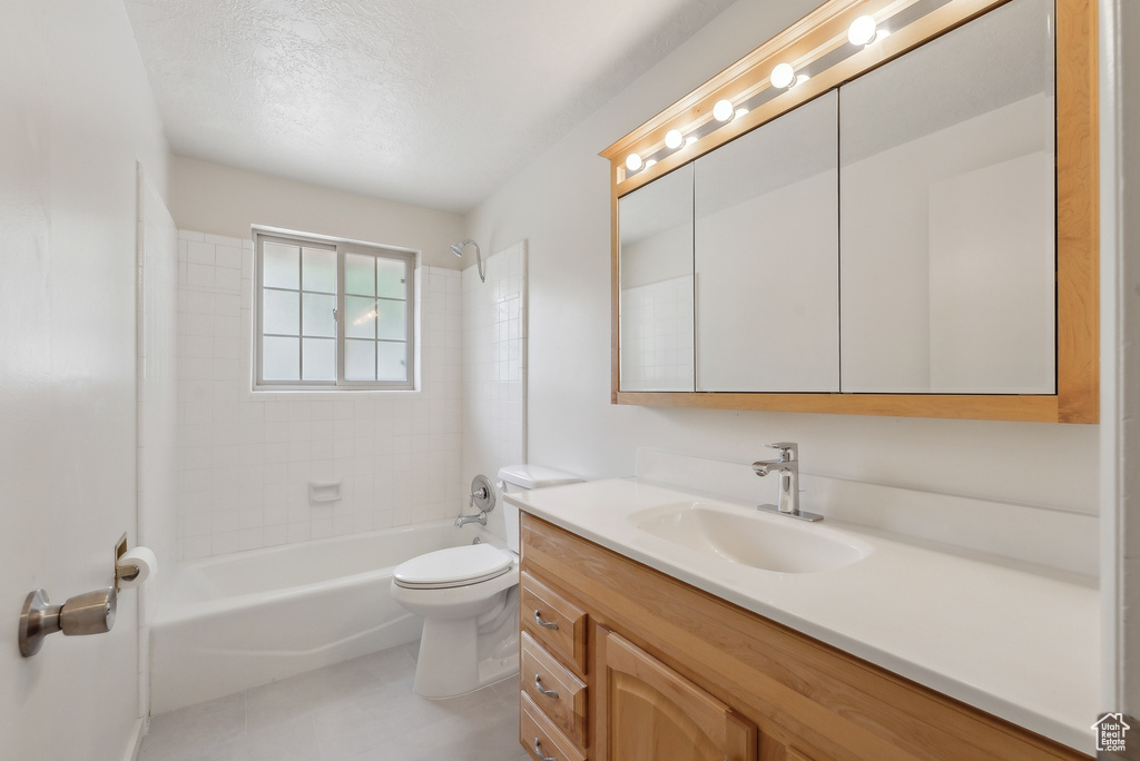 Bathroom featuring toilet, vanity, bathtub / shower combination, tile patterned flooring, and a textured ceiling