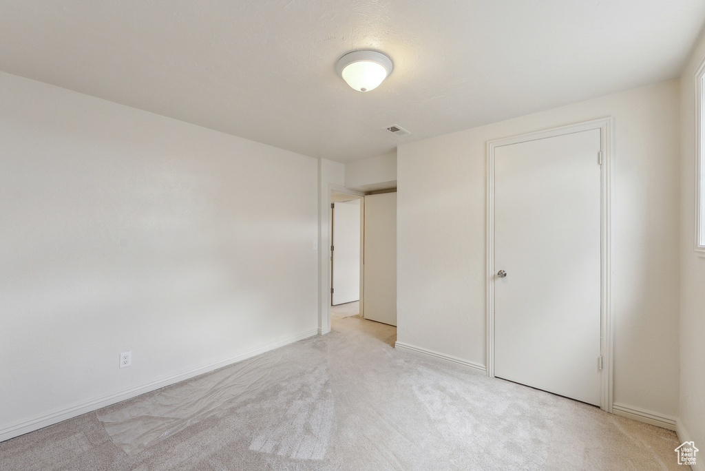 Unfurnished bedroom featuring light carpet and baseboards