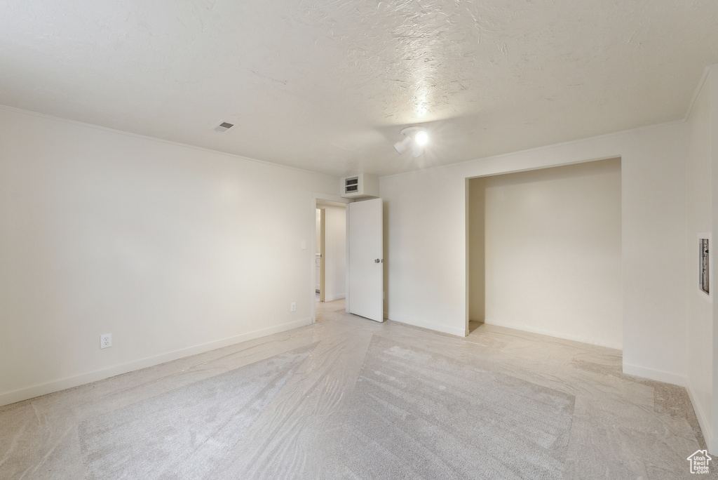 Spare room featuring light colored carpet, a textured ceiling, and baseboards