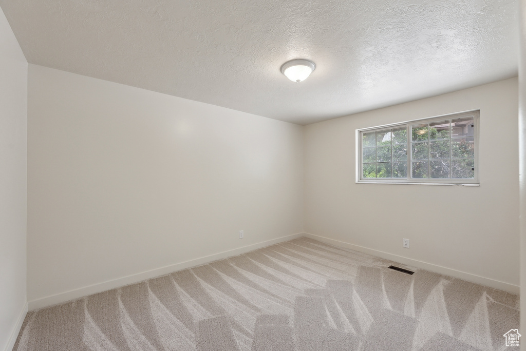 Unfurnished room with carpet flooring, baseboards, and a textured ceiling