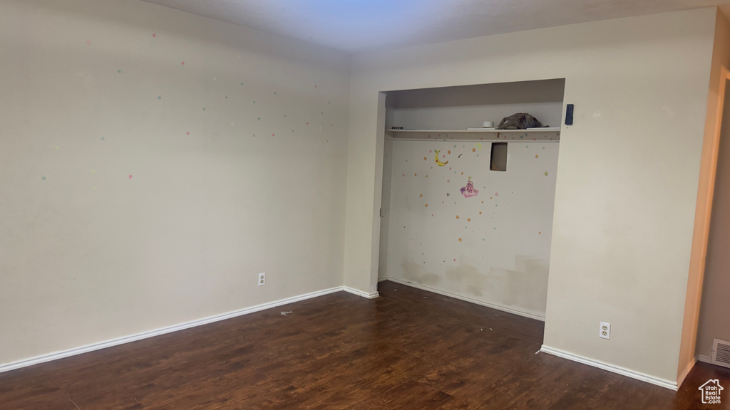 Unfurnished bedroom featuring wood finished floors, a closet, and baseboards