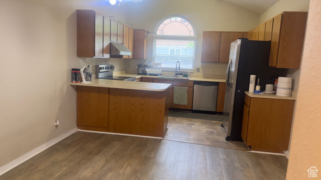 Kitchen featuring appliances with stainless steel finishes, under cabinet range hood, a sink, a peninsula, and light countertops