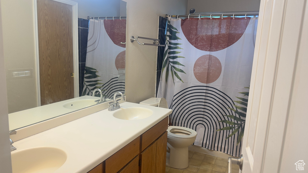Bathroom featuring toilet, double vanity, a shower with curtain, and tile patterned flooring