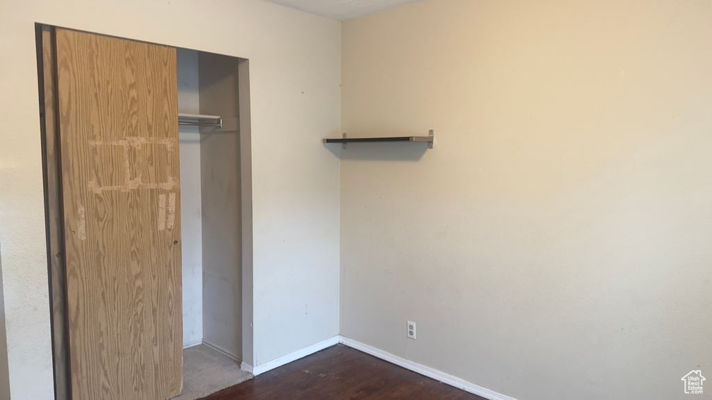 Unfurnished bedroom with baseboards, a closet, and dark wood-style flooring