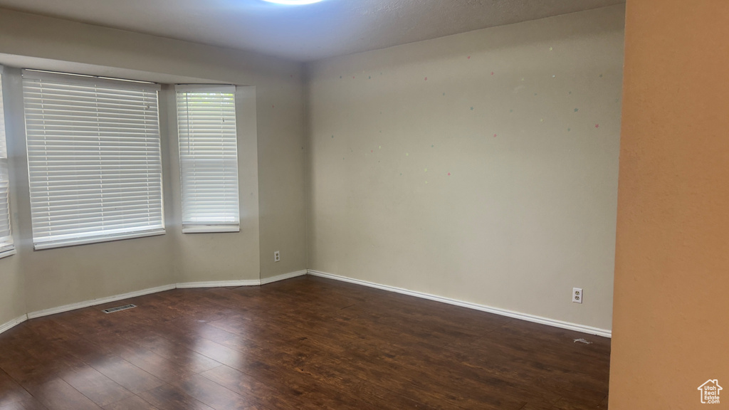 Spare room featuring wood-type flooring and baseboards