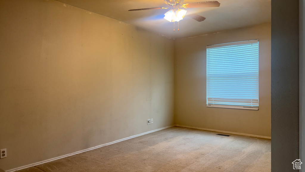 Spare room featuring a ceiling fan, baseboards, and light carpet