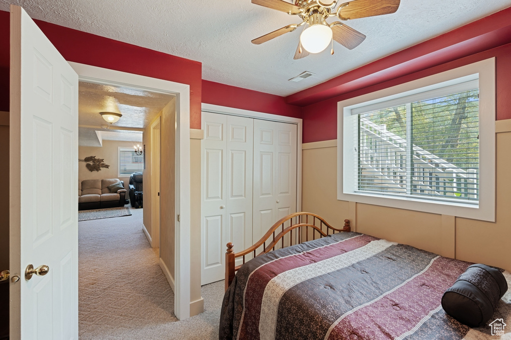 Carpeted bedroom with a textured ceiling, a closet, and ceiling fan