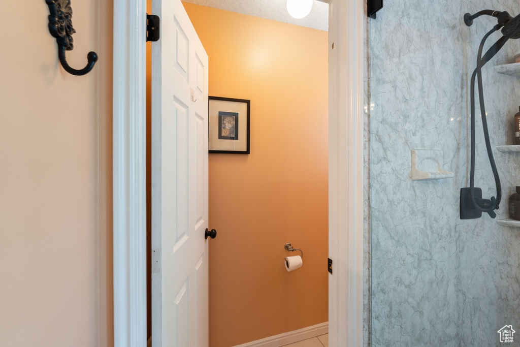 Bathroom featuring baseboards, a shower, and tile patterned flooring