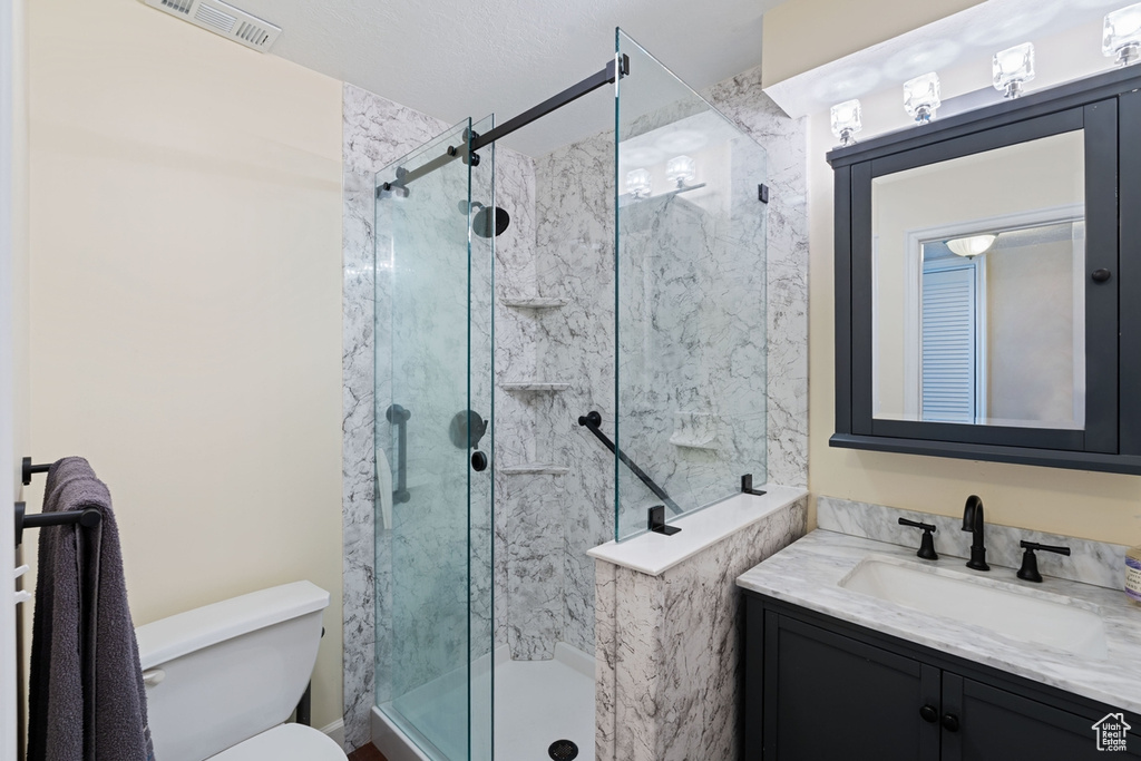 Bathroom with a shower stall, toilet, and vanity