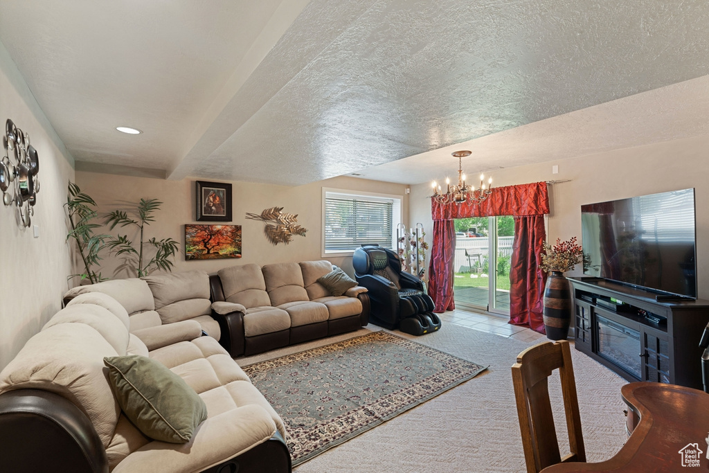Carpeted living area featuring a chandelier, beamed ceiling, and a textured ceiling