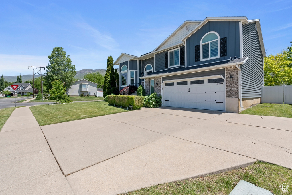 View of front of home with board and batten siding, a garage, driveway, and a mountain view
