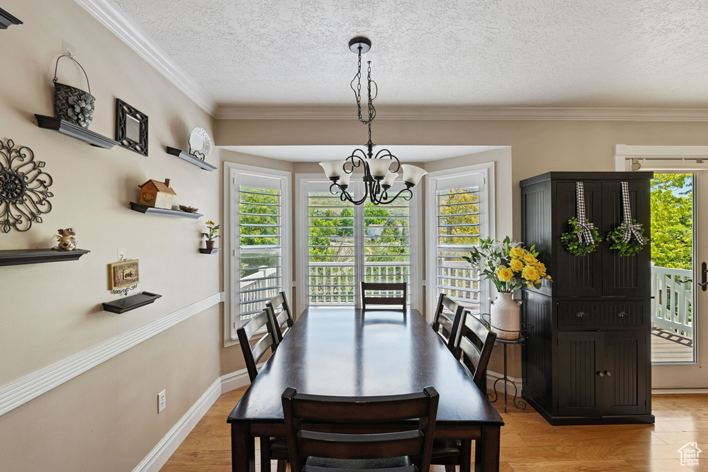Dining room featuring a chandelier, a textured ceiling, ornamental molding, and baseboards