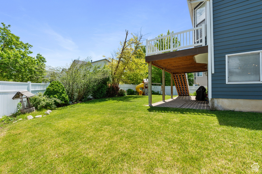 View of yard featuring a wooden deck and a playground